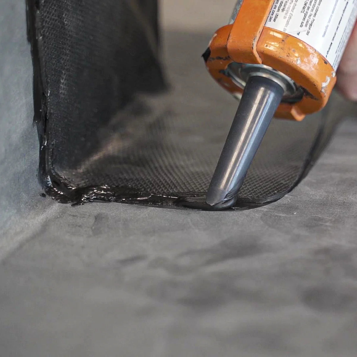 Lap sealant being applied around the edges of uncured epdm flashing tape on a rubber roof