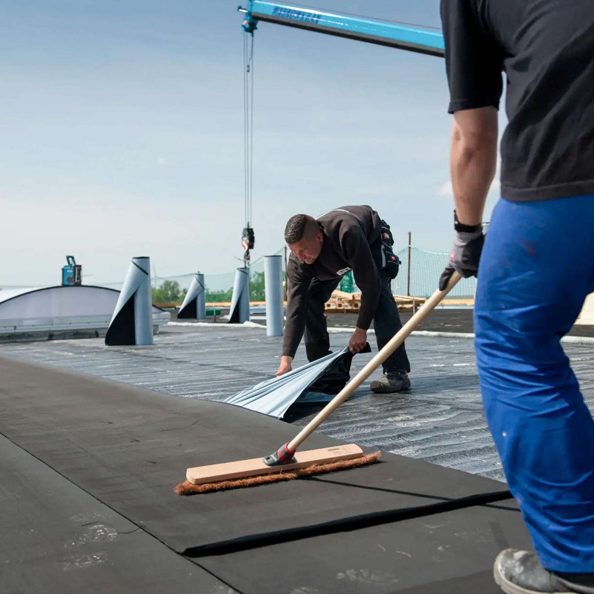 resitrix self-adhesive epdm being installed over fg35 primer by 2 installers on a commercial flat roof