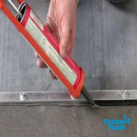 termination bar detail on a rubber roof being finish by applying a bead of lap sealant with a caulking gun